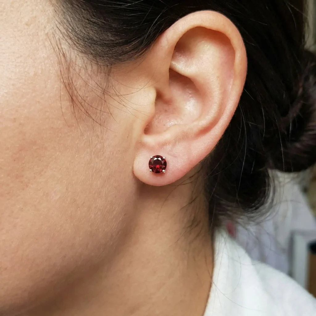 woman wearing 5mm round cut garnet solitaire stud earrings