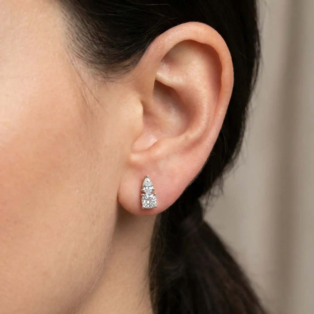 woman wearing cushion and pear two stone lab grown diamond stud earrings