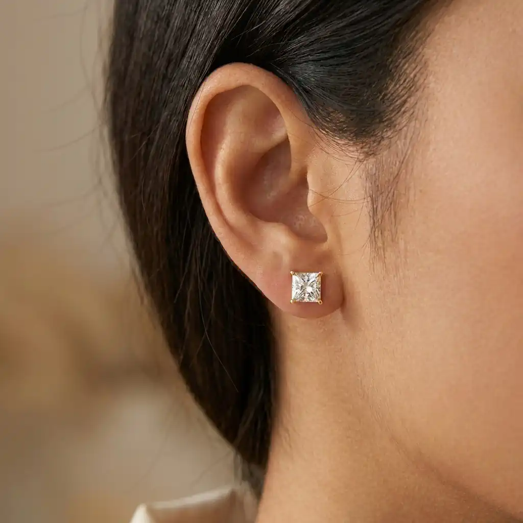 Woman wearing KRKC princess cut moissanite stud earrings in white gold plated sterling silver