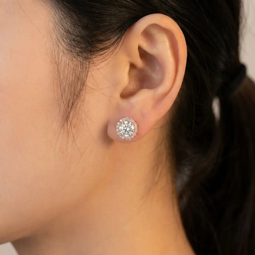 Woman wearing KRKC round moissanite stud earrings in white gold plated sterling silver