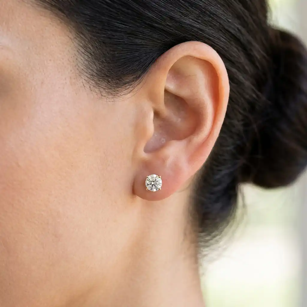 Woman wearing Amazon Essentials lab grown diamond stud earrings 14K gold round cut solitaire