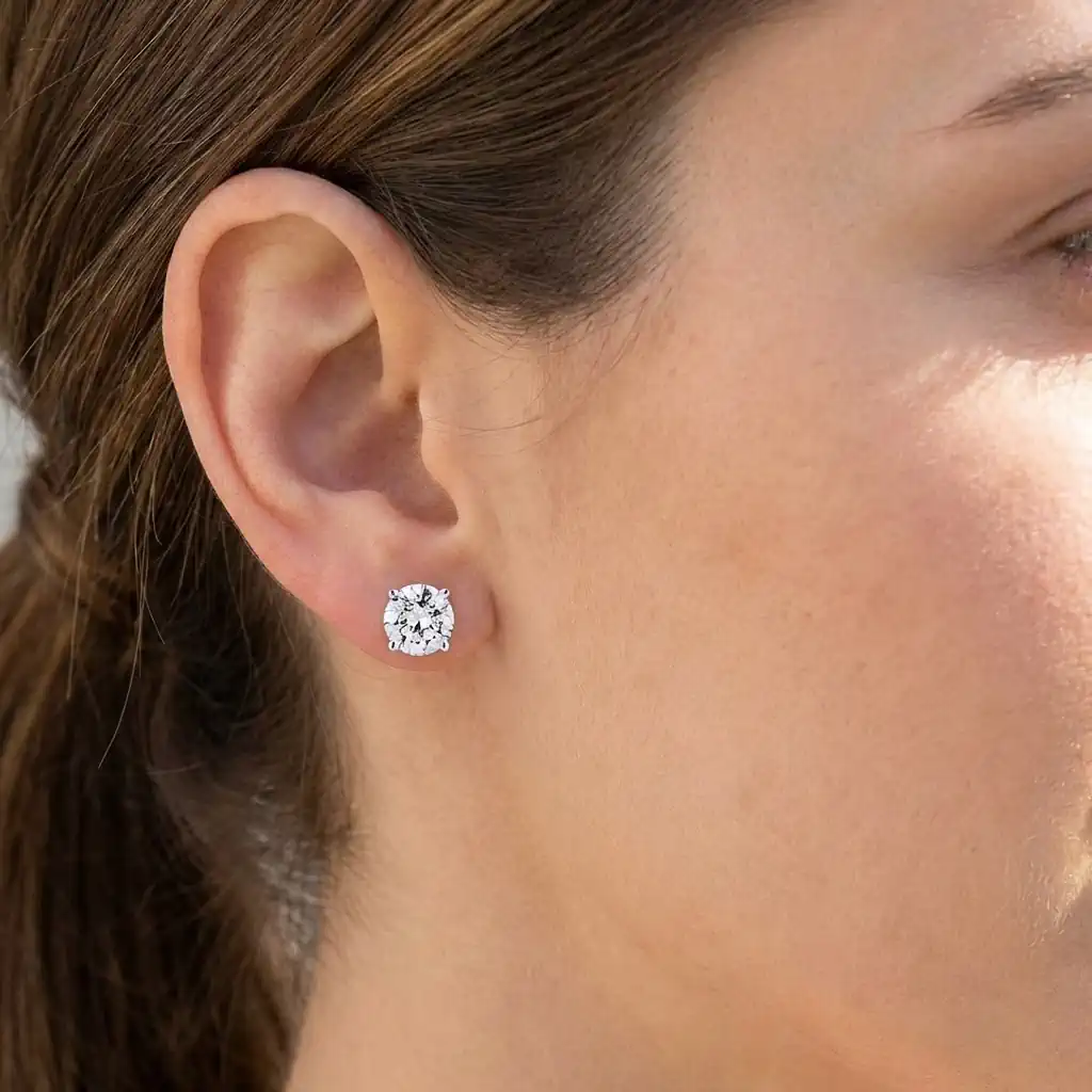Woman wearing round lab grown diamond stud earrings 14K gold screw back elegant diamond studs